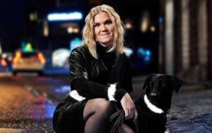 Kvinde og sort hund i mørket med lysende Smart in the dark reflekser på bælte, ærme, hundehalsbånd og snor.