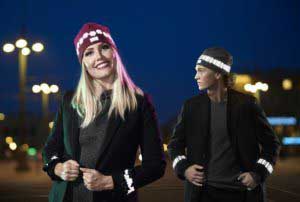 To søte jenter med refleksluer og rynkede refleksarmbånd fra Smart in the Dark på tur i byen om kvelden.