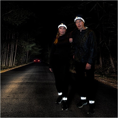 En jente og en gutt som er ute og løper i mørket. De har på seg treningsluer med refleks fra Smart in the Dark.