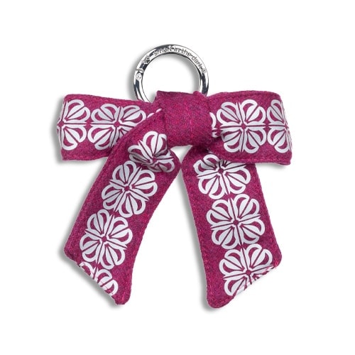 Smart reflex till väskan i form av en rosett. I färgen anemonrosa med reflexmönster av fyrklöver.