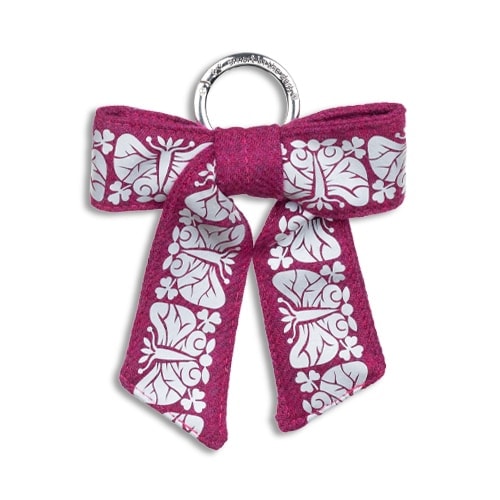 Smart smycke till väskan i form av en reflexrosett. I färgen anemonrosa med reflexmönster av nattfjäril.