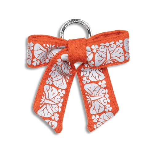 Smart smycke till väskan i form av en reflexrosett. I orange med reflexmönster av nattfjäril.