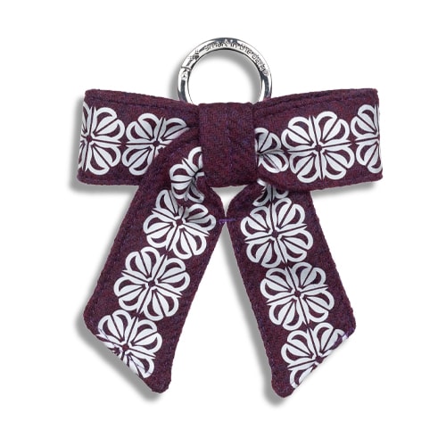 Smart reflex till väskan i form av en rosett. I färgen skogsgrön med reflexmönster av fyrklöver.