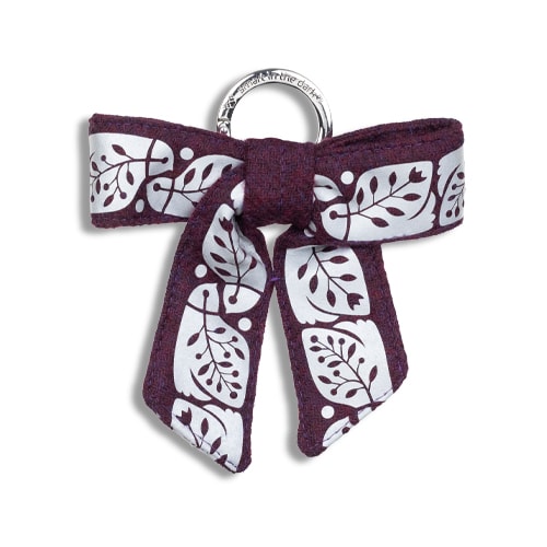 Vackert smycke till väskan i form av en reflexrosett. I färgen plommon med reflexmönster av nattskärra.