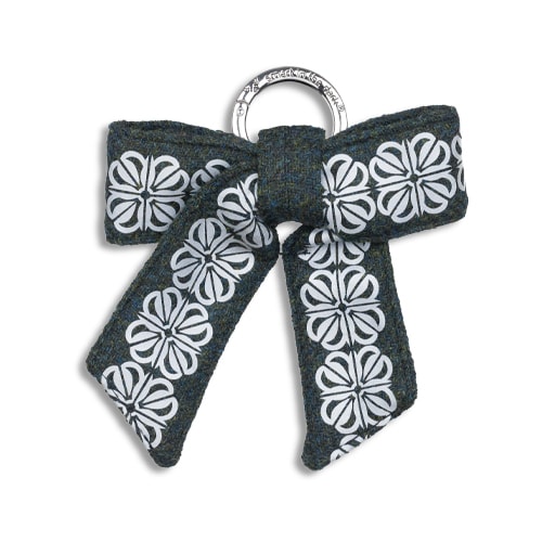 Smart reflex till väskan i form av en rosett. I färgen skogsgrön med reflexmönster av fyrklöver.