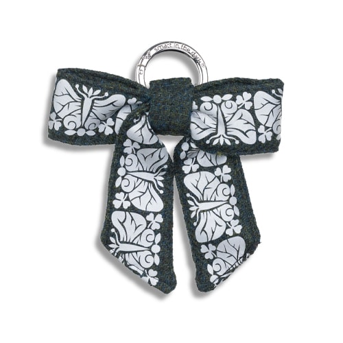 Smart smycke till väskan i form av en reflexrosett. I färgen skogsgrön med reflexmönster av nattfjäril.