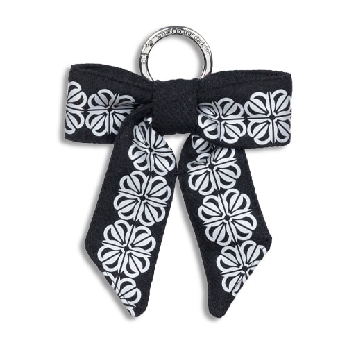 Smart reflex till väskan i form av en rosett. I färgen svart med reflexmönster av fyrklöver.