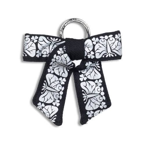 Smart smycke till väskan i form av en reflexrosett. I färgen svart med reflexmönster av nattfjäril.