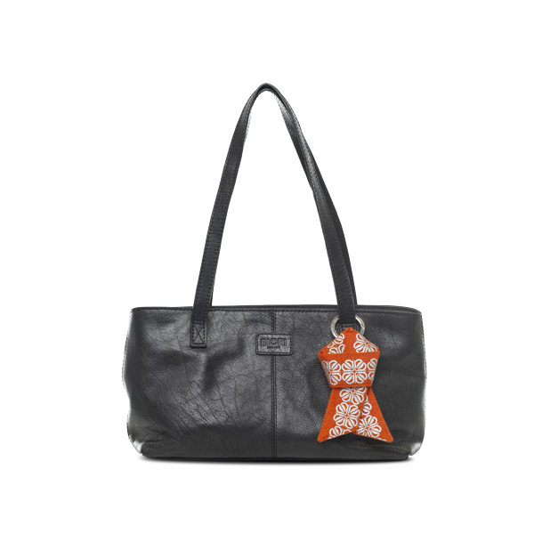 Reflex till väskan i form av en knut. I färgen orange med reflexmönster av fyrklöver