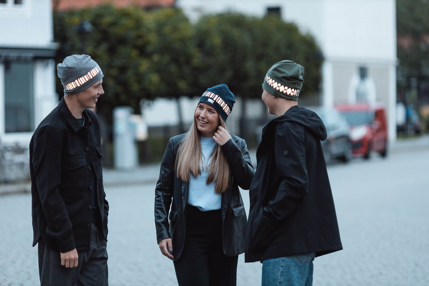 Young adults wearing reflective beanie hats from smart in the dark out in traffic